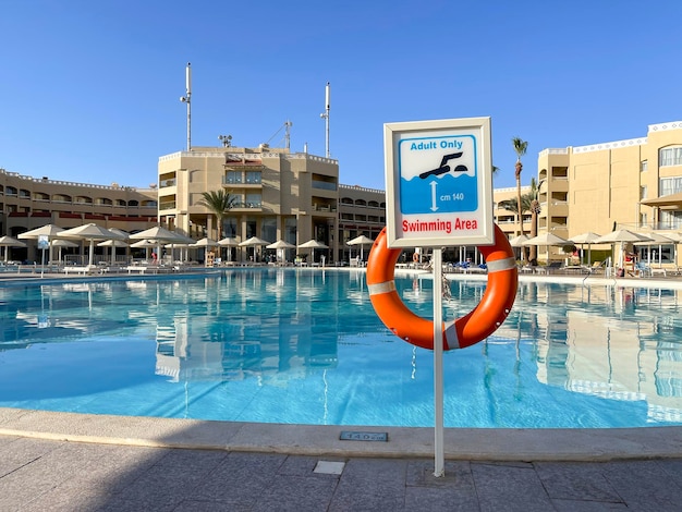 Aro salvavidas y cartel Zona de baño Solo adultos en la piscina