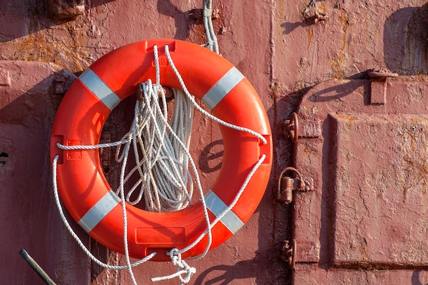 El aro salvavidas con cuerda está colgado en la pared de metal del barco.