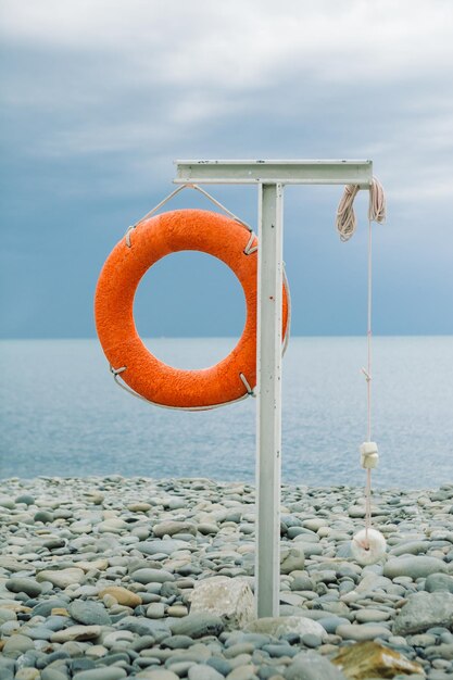 Foto aro salvavidas naranja en la costa del mar en un día nublado