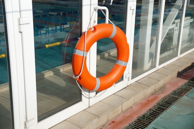 Aro salvavidas naranja en una pared de una protección de la piscina