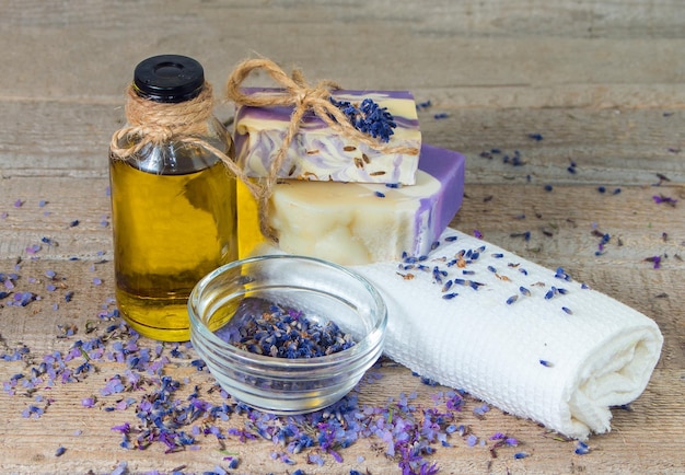 Foto aroma óleo de lavanda flores sabonete artesanal e toalhas brancas de banho em fundo de madeira cosméticos naturais para cuidados com o corpo
