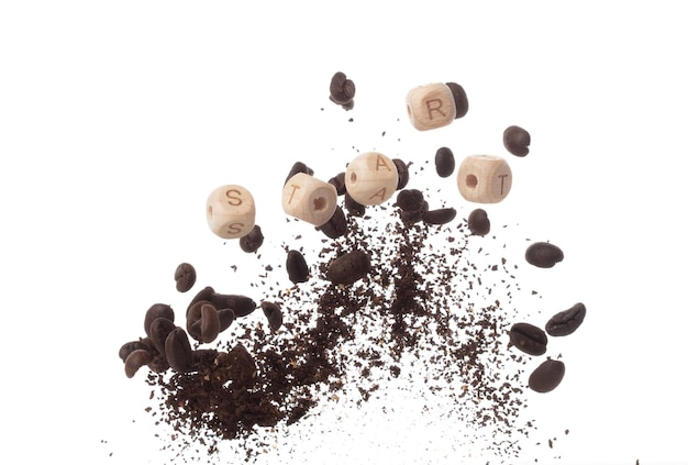 Aroma rico granos de café recién tostados vuelan en el aire mientras bailan junto a bloques de letras del alfabeto cuentas de juguete START encarnando la esencia de la semilla de café en polvo fondo blanco explosión aislada