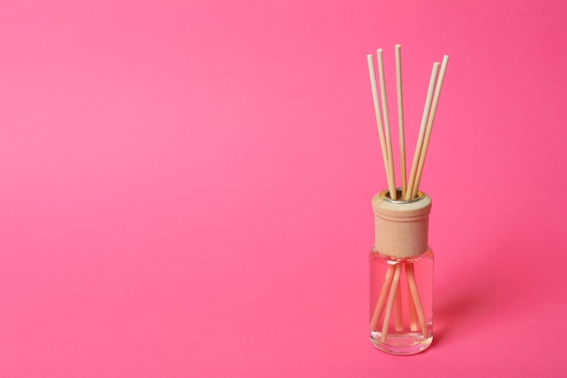 Aromaduftdiffusor mit Stäbchen auf rosa Hintergrund