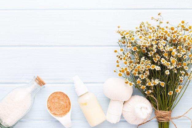 Aromaterapia de composição com cosméticos naturais e flores de camomila em fundo claro.