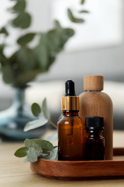 Aromaterapia Garrafas de óleo essencial e folhas de eucalipto em mesa de madeira