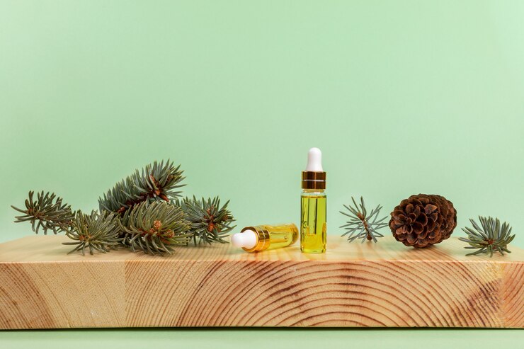 Aromatherapie und Spa-Komposition mit ätherischem Fichtenöl in kleinen Glasflaschen, grünen Zweigen und Kegel auf hölzernem Buchsbaumständer auf hellgrünem Hintergrund. Kopieren Sie Platz für Text.