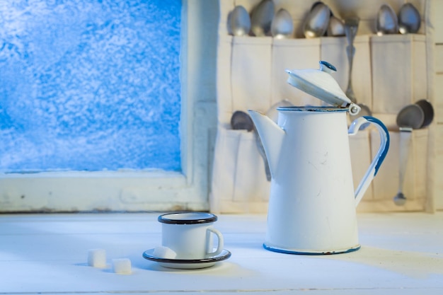 Aromatische Kaffeekanne und Tasse mit Löffeln durch gefrorenes Fenster