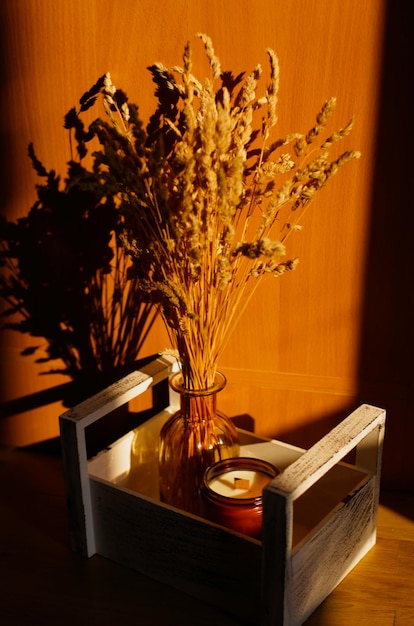Foto aromatische kerze und trockene blumen, das konzept des gemütlichen herbstes