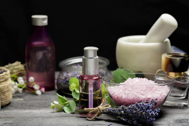 Aromatische Komposition aus Lavendel, Kräutern, Kosmetik und Salz auf dunkler Tischplatte