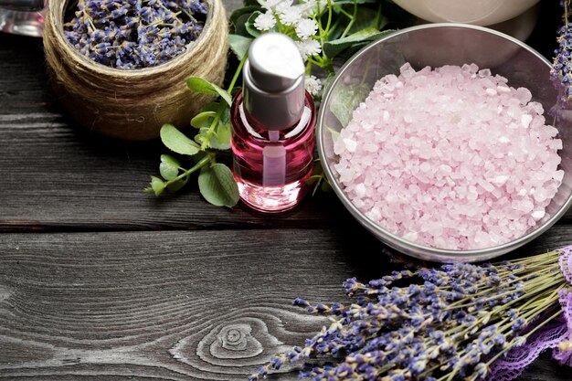 Aromatische Komposition aus Lavendel, Kräutern, Kosmetik und Salz auf dunkler Tischplatte