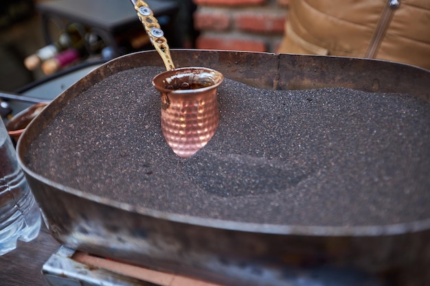 Aromatischer Kaffee gebraut in heißem Sand türkischer Kaffee, der in Cezve-Qualitätsfoto gebrüht wird