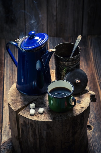 Aromatischer und heißer schwarzer Kaffee auf Holzstumpf