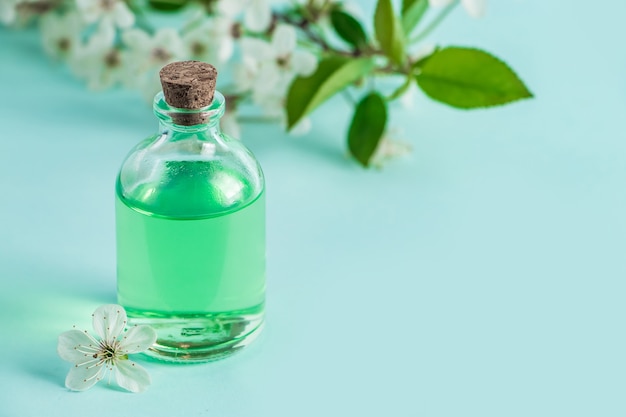 Aromatisches ätherisches Öl in Glasflasche und Blumen auf blauem Hintergrund Aromatherapie und Spa-Konzept