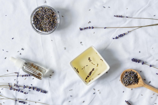 Aromatisches ätherisches und Massageöl mit Lavendelblüten auf weißem Hintergrund