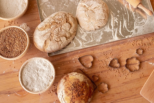Aromatisiertes frisches Brot und Backzubehör für Teig auf dem Tisch