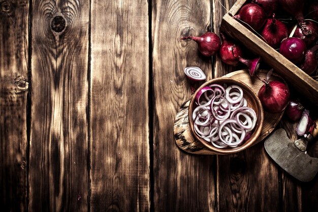 Aros de cebolla en rodajas en una taza sobre el tronco de un árbol en la mesa de madera.