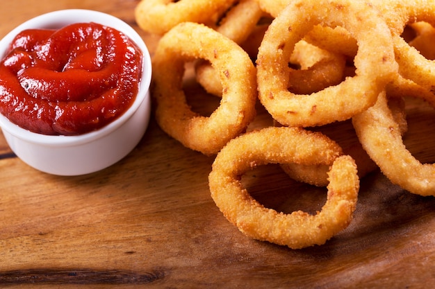 Aros de cebolla con salsa de tomate sobre tabla de madera