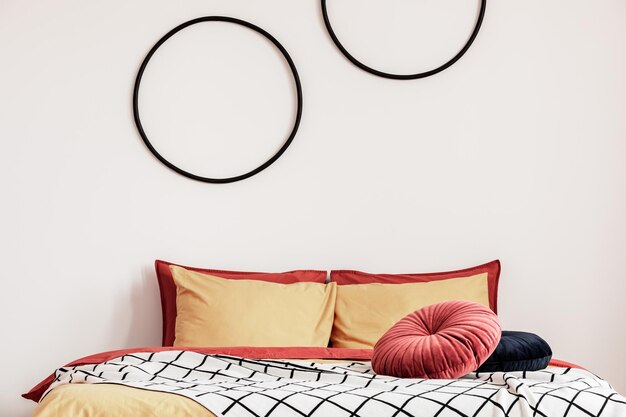 Aros negros en una pared blanca en un elegante dormitorio con ropa de cama naranja en la cama