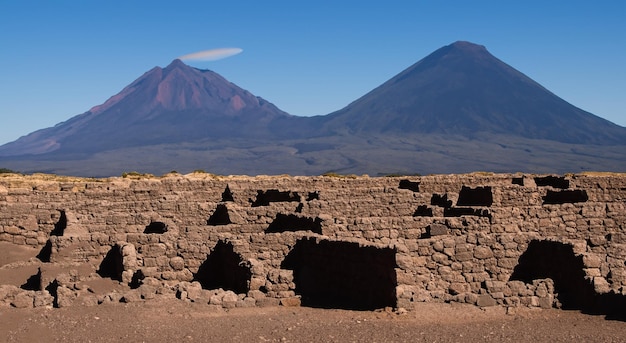 Arqueologia antiga de casas de pedra com um vulcão ao fundo em alta resolução