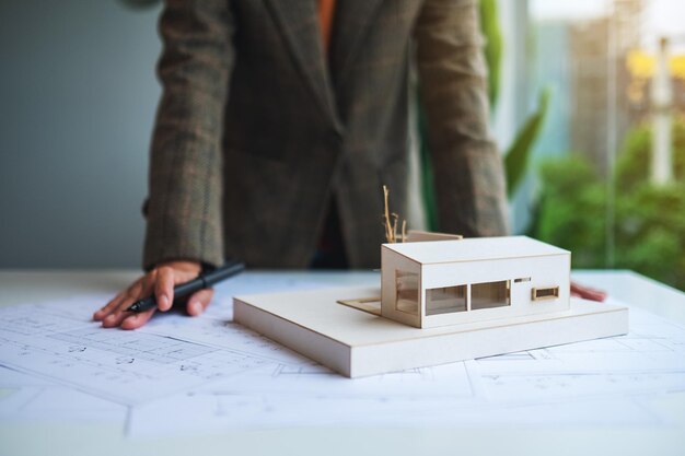 Una arquitecta trabajando en un modelo de casa de arquitectura con papel de dibujo de tienda en la oficina