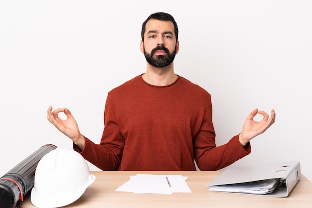 Arquitecto caucásico hombre con barba en una mesa en pose zen