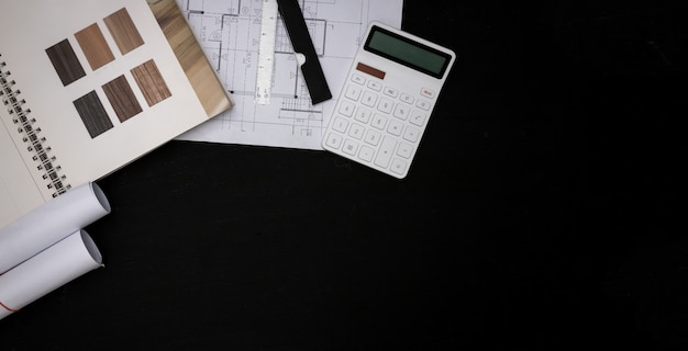 El arquitecto diseñó el edificio en la oficina de diseño, el plano con catálogos de materiales decorativos y otros accesorios en la mesa de madera negra.