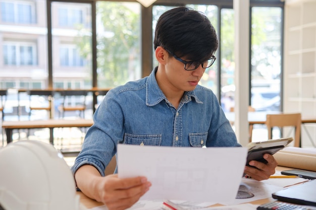 Arquitecto e ingeniero revisando planos y usando una tableta en una oficina moderna