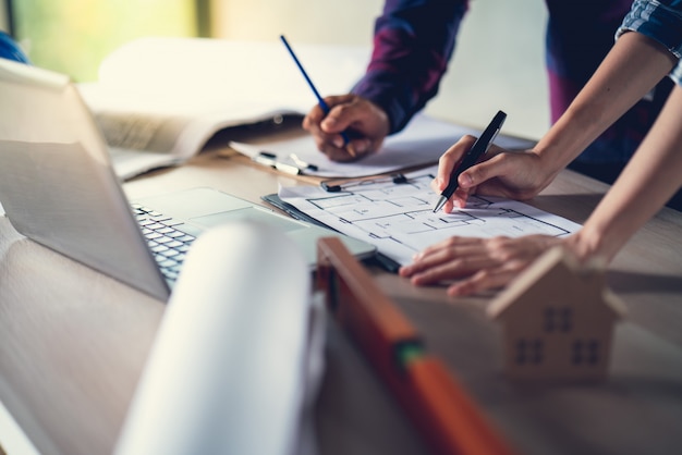 Arquitecto e ingeniero trabajando en un documento de dibujo sobre la planificación del proyecto y el progreso del cronograma de trabajo en el sitio de construcción del edificio de viviendas,