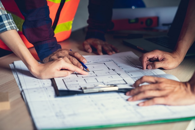 Arquitecto e ingeniero trabajando en un documento de dibujo sobre la planificación del proyecto y el progreso del cronograma de trabajo en el sitio de construcción del edificio de viviendas,