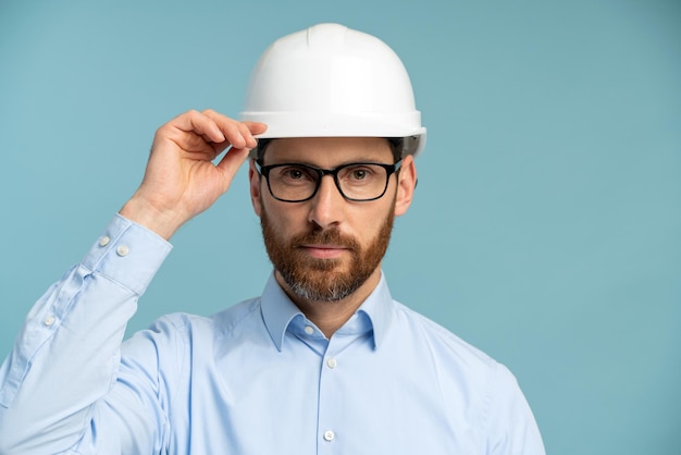 Arquitecto hombre con rostro serio en casco de seguridad constructor mirando a la cámara a través de sus gafas sobre fondo aislado Concepto de ingeniero