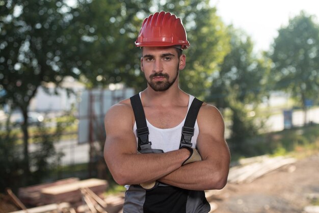 Arquitecto masculino exitoso en un sitio de construcción con los brazos cruzados