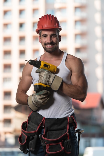 Arquitecto masculino exitoso en un sitio de construcción con taladro