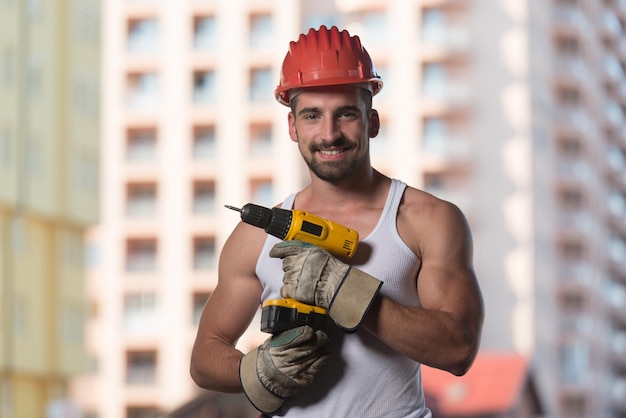 Arquitecto masculino exitoso en un sitio de construcción con taladro