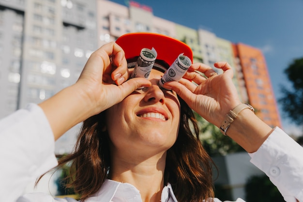 Arquitecto de mujer de negocios en casco mira a través de billetes de un dólar como símbolo de compromiso. negocio