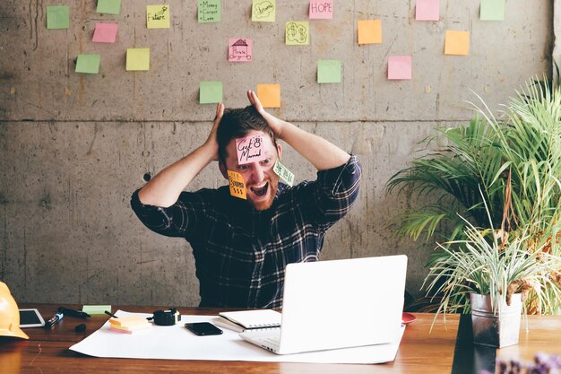 Foto arquitecto con notas adhesivas en la cara en la oficina