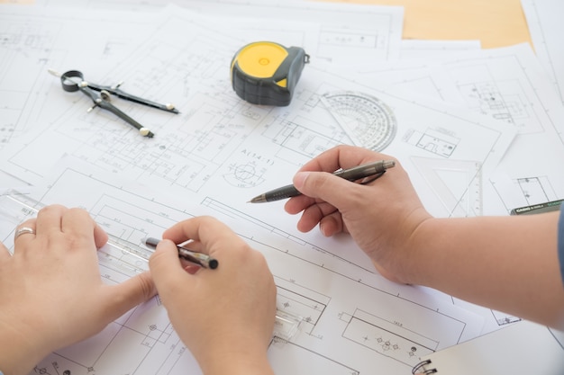 Arquitecto o planificador trabajando en dibujos para planos de construcción en una mesa