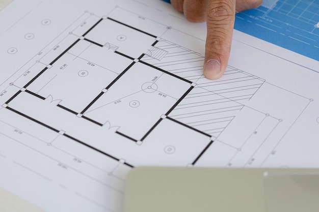Arquitecto señalando los planos de construcción para revisarlos y editarlos Los ingenieros arquitectos diseñan casas y estructuras interiores y dibujan planos a través del programa de diseño Arquitecto concepto de diseño de edificios