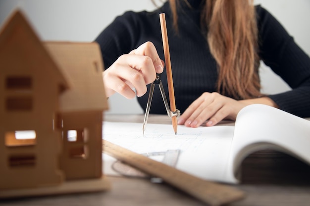 Arquitecto de sexo femenino que trabaja con planos en el escritorio de oficina