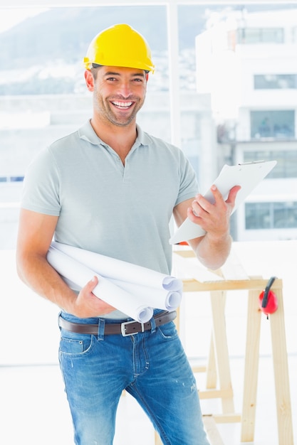 Foto arquitecto sonriente con planos y portapapeles en la oficina