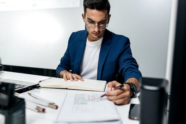 Foto el arquitecto vestido con una chaqueta azul oscuro trabaja con documentos en el escritorio de la oficina.