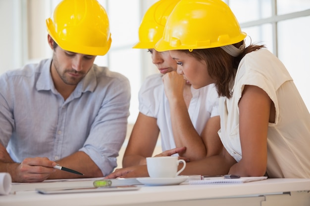 Arquitectos en cascos amarillos trabajando en planos