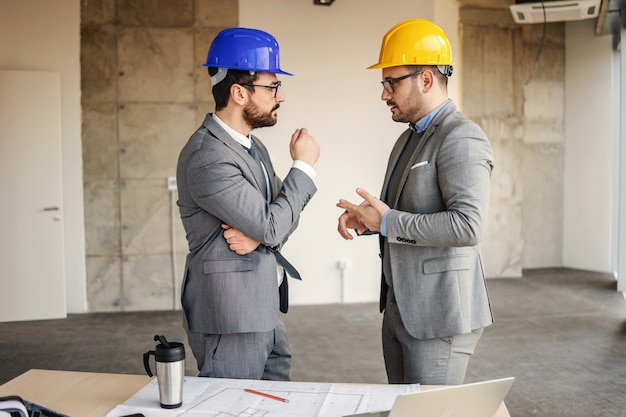 Arquitectos discutiendo sobre su proyecto mientras están de pie en un edificio en proceso de construcción