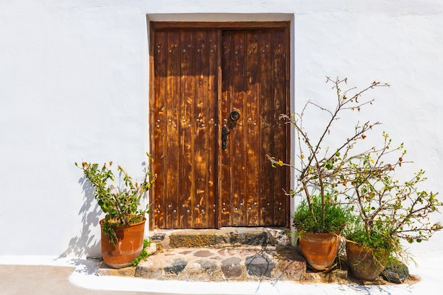 Arquitectura blanca de las Cícladas en la isla de Santorini Grecia Fachada blanca de la casa y puerta de madera con flores