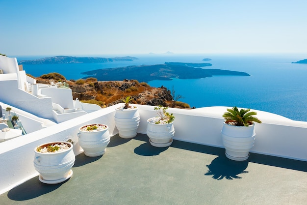 Arquitectura blanca en la isla de Santorini, Grecia. Flores en la terraza con vista al mar.