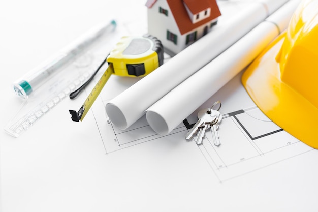 arquitectura, construcción, construcción, bienes raíces y concepto de hogar: cierre del plano arquitectónico con herramientas y llaves de la casa