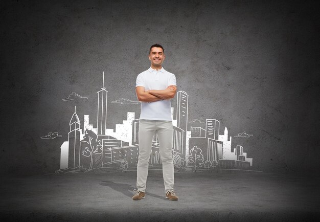 arquitectura, desarrollo y concepto de la gente - hombre sonriente con camiseta blanca con los brazos cruzados sobre el boceto de la ciudad y el fondo de hormigón