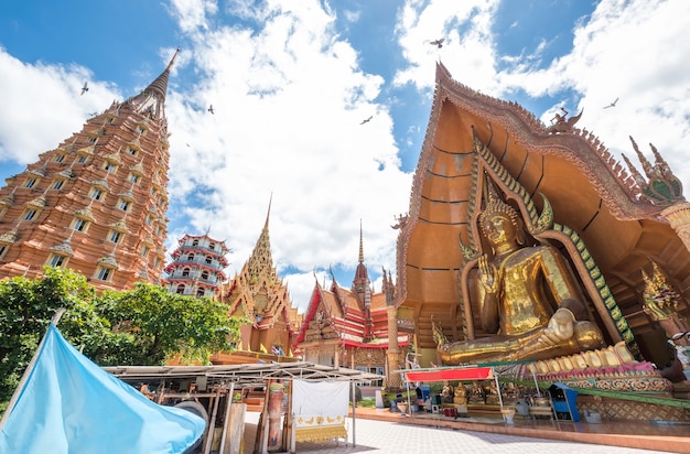 Arquitectura iglesia dorada con gran buda y pagoda en Wat Tham Sua, Kanchanaburi, Tailandia