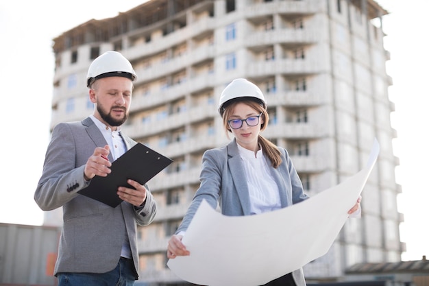 Arquitectura profesional masculina y femenina trabajando juntos en el sitio.