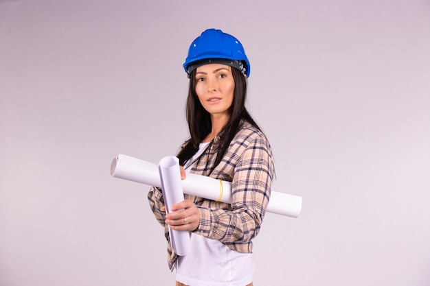 Arquiteta com capacete em um fundo branco e isolado, com um projeto em mãos, olha para a câmera