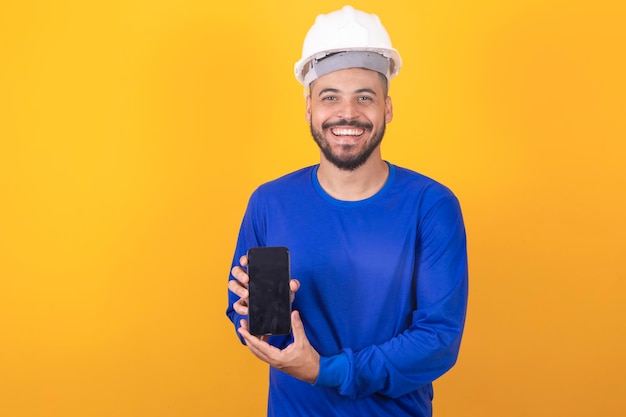 Arquiteto de homem bonito segurando smartphone com tela em branco com espaço livre para texto em fundo amarelo